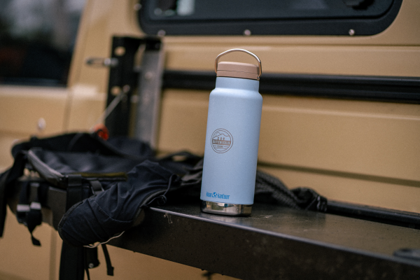Light blue Klean Kanteen water bottle on a vehicle's tailgate